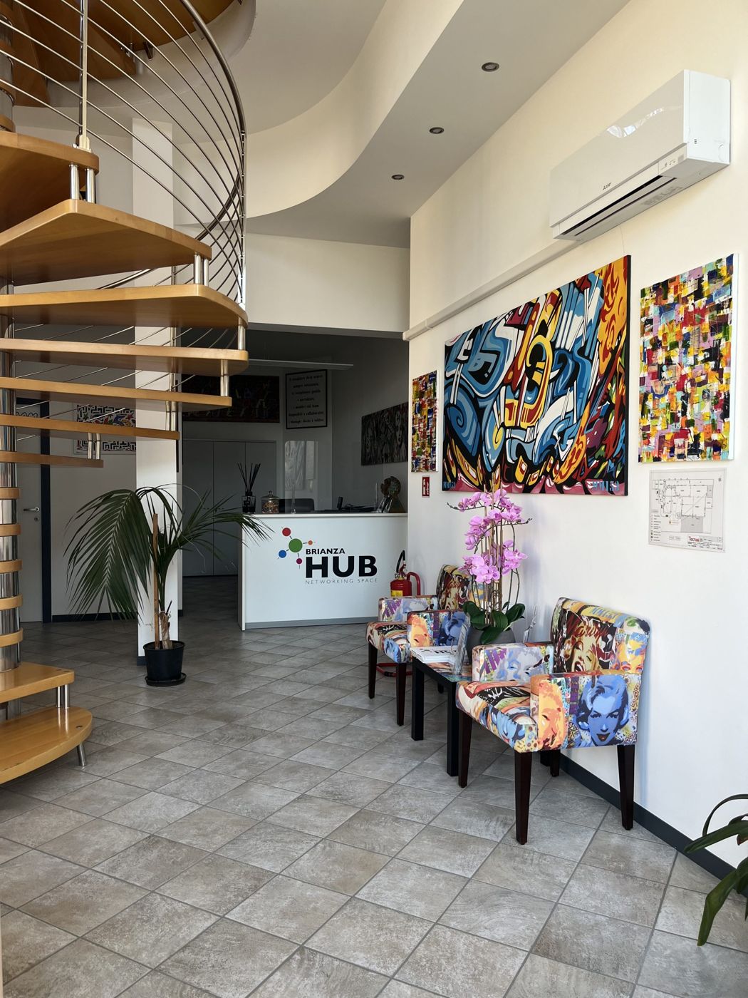 La reception di Brianza Hub con il bancone e le opere d'arte alle pareti