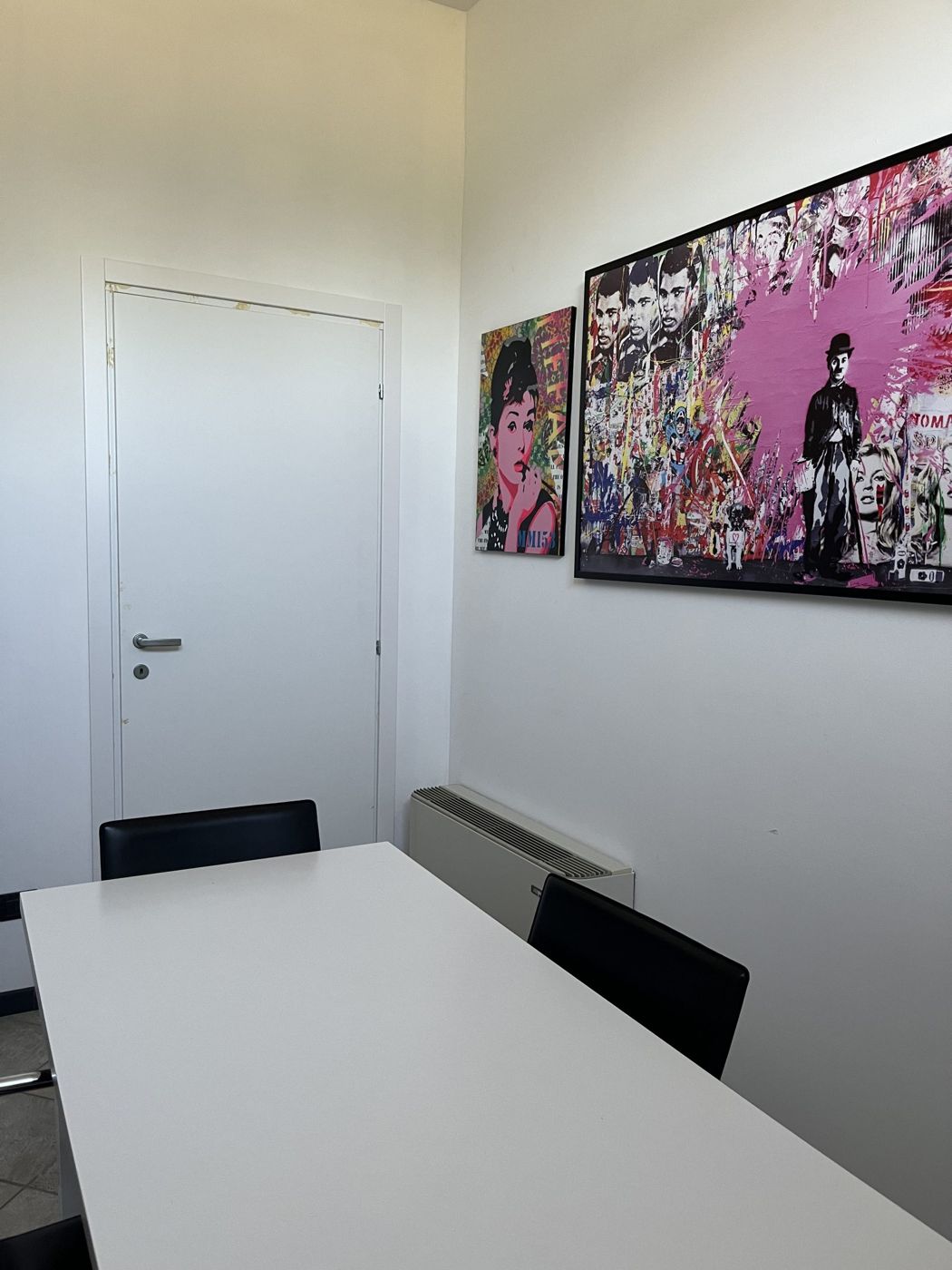 Sala riunioni con tavolo bianco e quadri pop art
