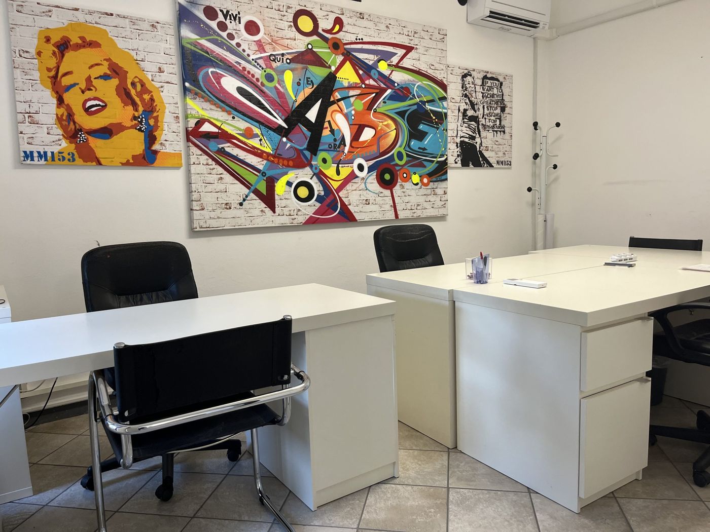 Ufficio con scrivanie bianche e opere pop art