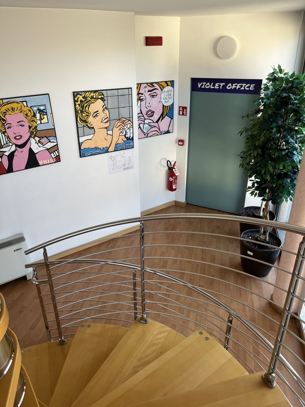 Pianerottolo con quadri pop art e porta del Violet Office